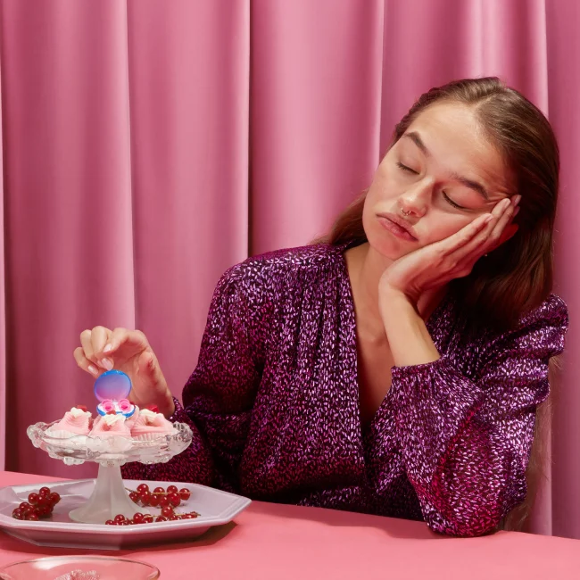 Woman looking at a plate of cupcakes with a pair of Loops on top.
