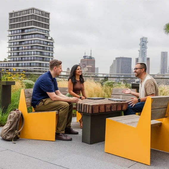 A picture of three people sitting together outside with an urban background
