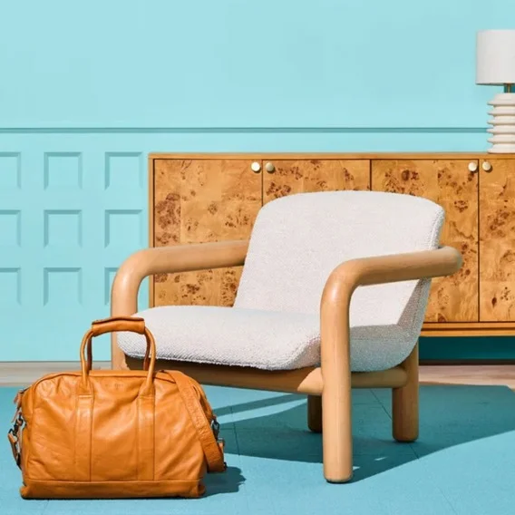 Image of a white chair sitting next to a brown leather bag.