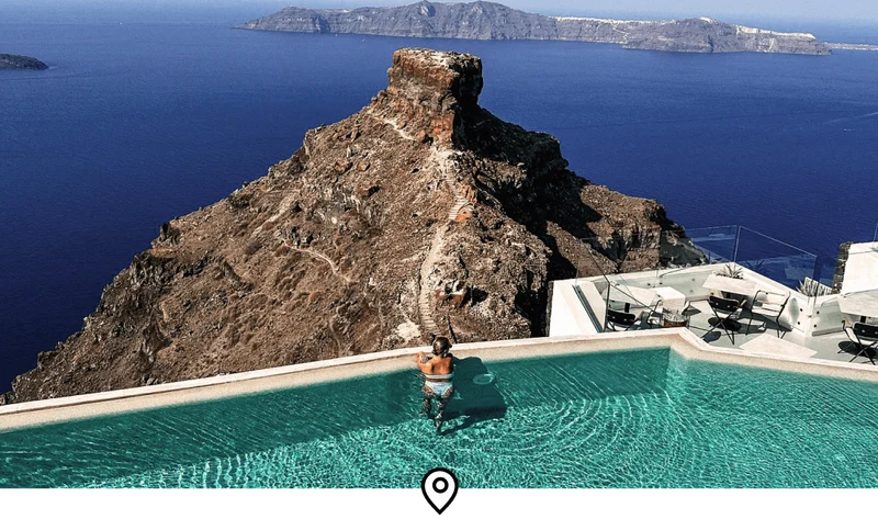 Image Description: A female traveler enjoying unobstructed views of the Santorini caldera from an infinity pool at Grace Hotel