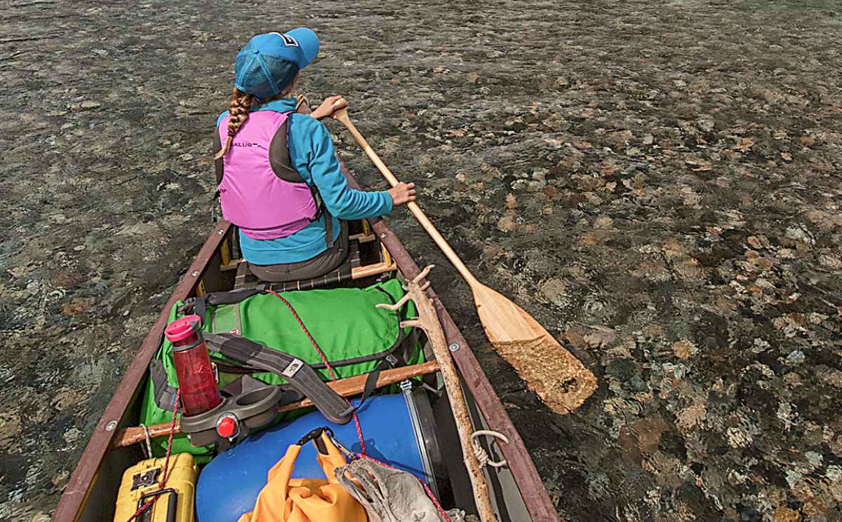 Patagonia. A person paddles a canoe down a clear river.