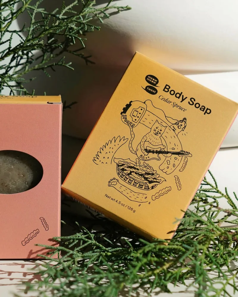 A mustard-yellow box sitting against a white planter with juniper greens