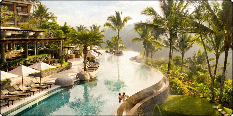 Image Description: Resort surrounded by lush greenery and nature with two people at the edge of an infinity pool.