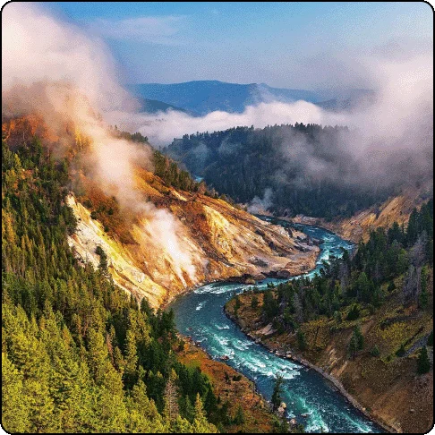 Image Description: Canyon with a river running down the center and mountains on both sides. Low clouds shadow parts of the mountain.