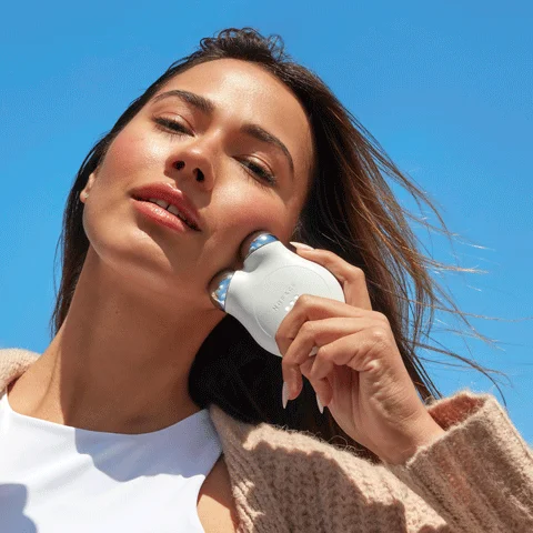 Woman holding MINI+ Device to her cheek to achieve a contoured look.