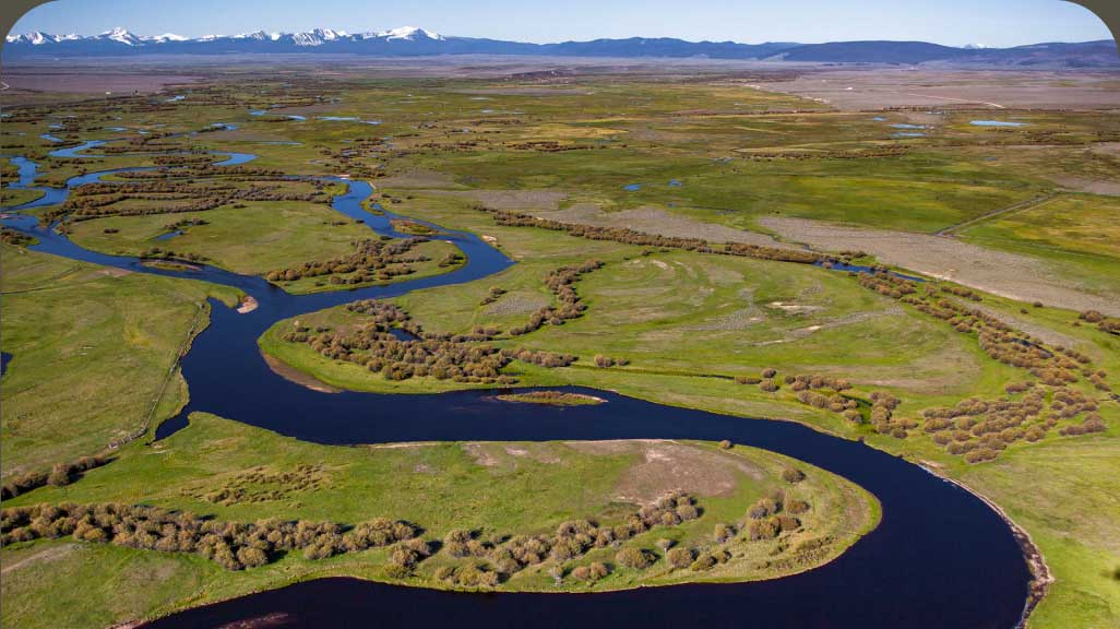 The Big Hole River in Montana winds through a green valley.