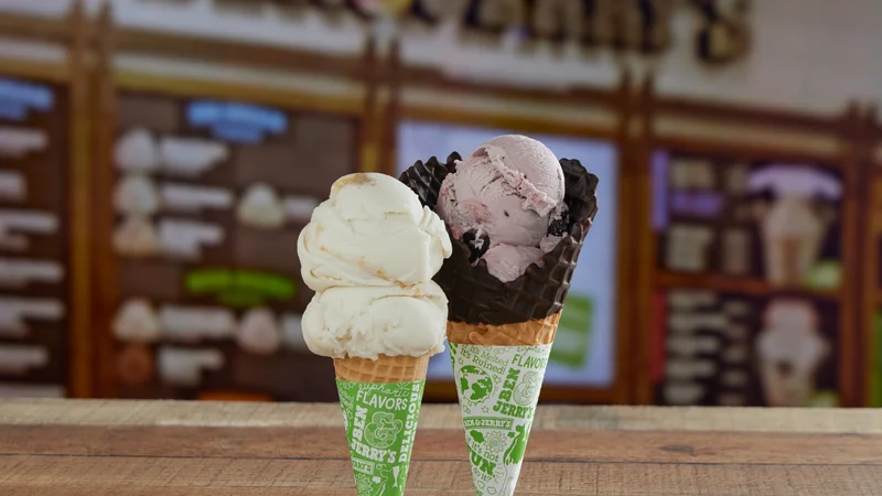 Two Ben & Jerry's ice cream cones, one with Key Lime Pie Non-Dairy, one with Black Raspberry Fudge Chunk ice cream. Scoop Shop setting.