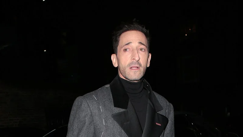 Image may contain: Adrien Brody, Clothing, Coat, Adult, Person, Overcoat, Footwear, Shoe, High Heel, Car, and Transportation
