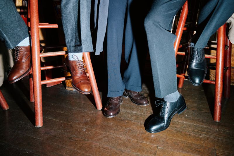 Three GQ staffers wearing men's Oxford shoes while sitting on barstools.