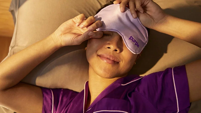 Woman laying in bed with Purple brand eye mask