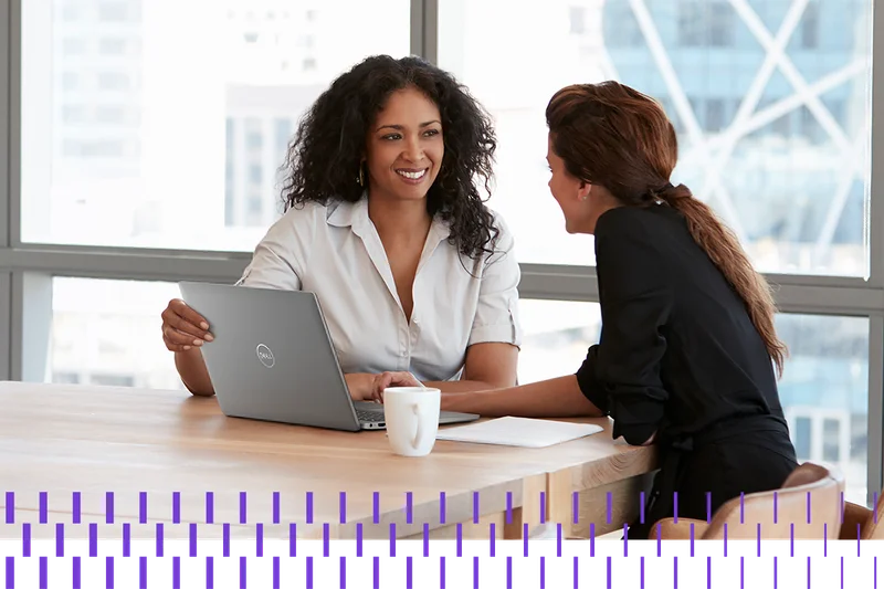 Two Businesswomen Using Laptop In Boardroom Meeting