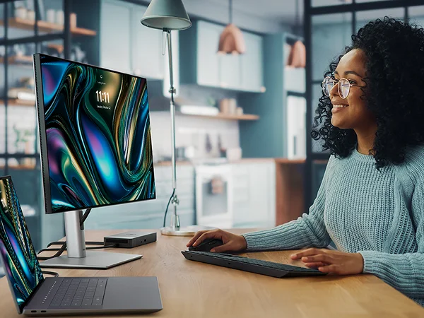 A Graphic Designer working on a Dell 16 Premium Laptop with a WD22TB4 docking station, 24 Ultrasharp Monitor, Pro Premium Collaboration Keyboard and Mouse.