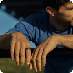 Person leaning on a fence wearing Oura Ring on right hand