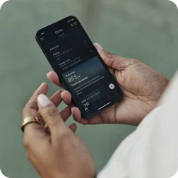 Hands holding phone with Oura app open wearing Oura Ring