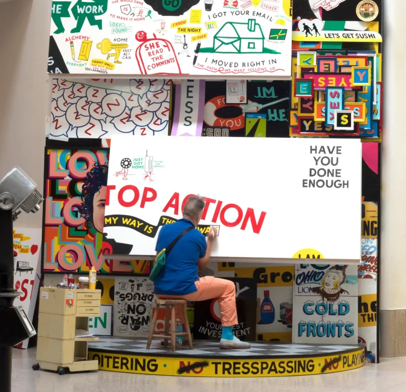 A man making a colorful sign with text that reads "HAVE YOU DONE ENOUGH"