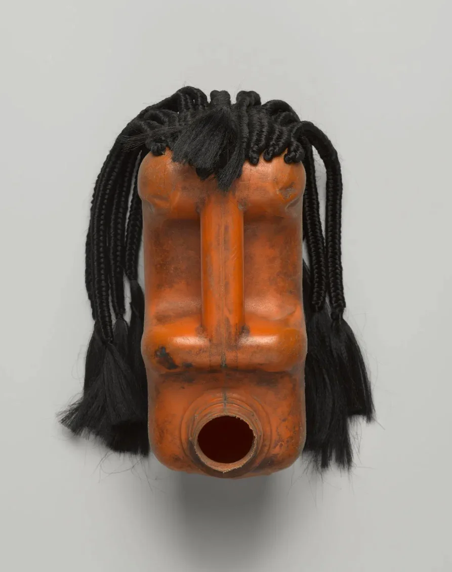 sculpture of a person's head made of oil can with long braids