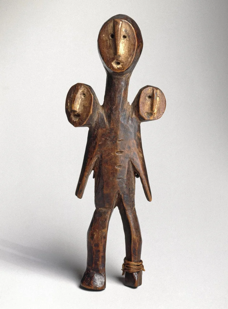 wooden sculpture of human figure with three heads