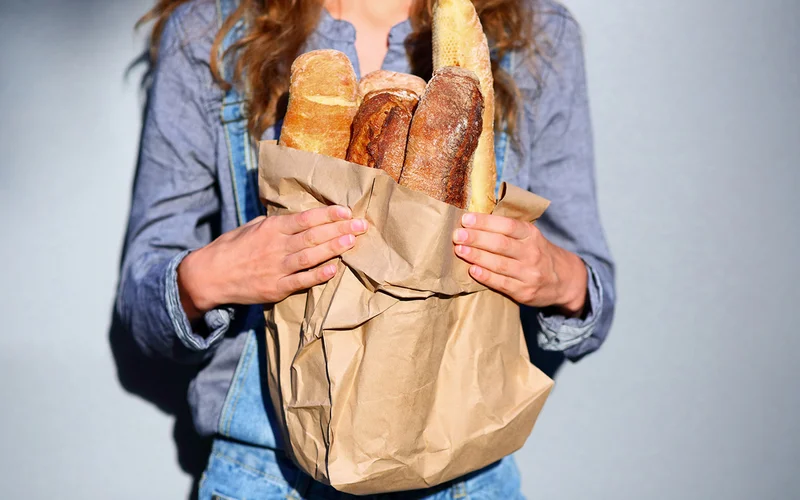 A person holding a bag of bread