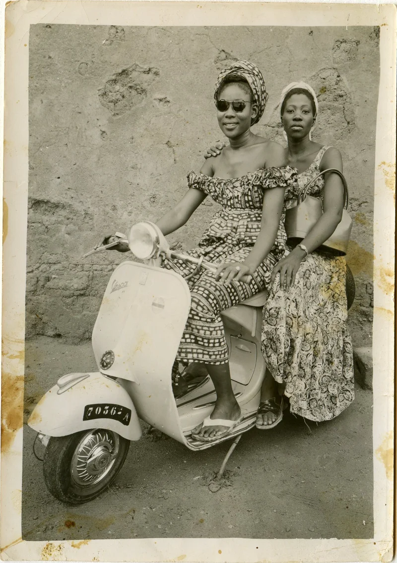 Two women posing on a Vespa