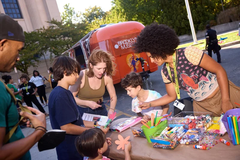 A group of adults and children art-making outside