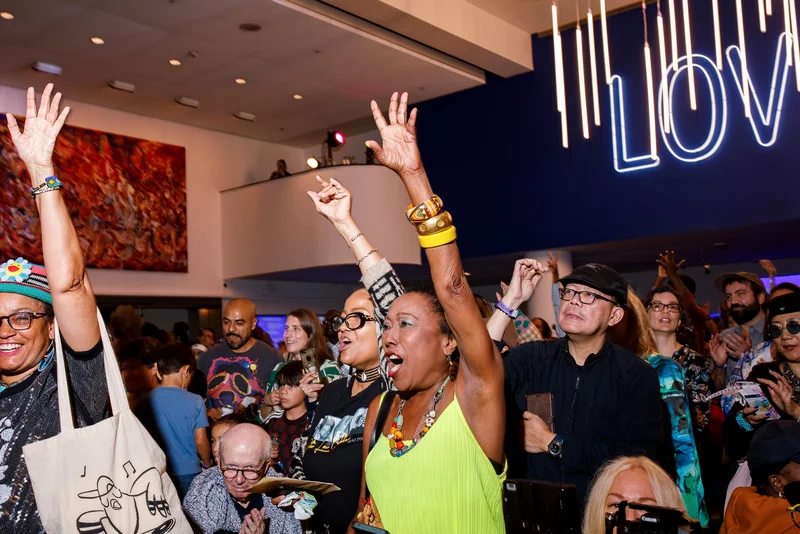 A group of people cheering with their hands in the air