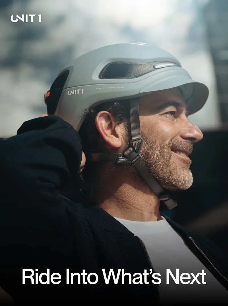 Man smiling and adjusting his UNIT 1 smart helmet, ready for the ride ahead.