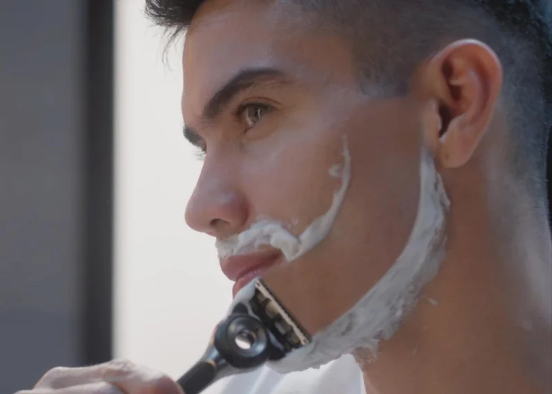 Young man shaving his face with Gillette razor