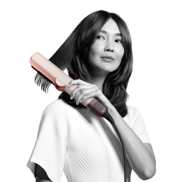 A model styling her hair with the Dyson Airstrait straightener