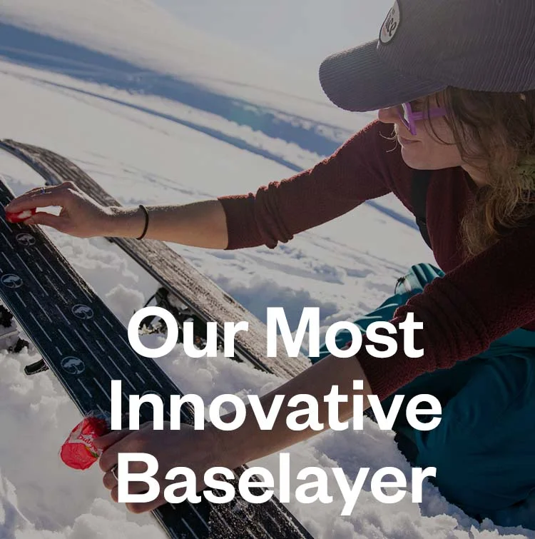 Patagonia 50. Our most innovative baselayer. A person kneeing in the snow rubs a small piece of cheese on the bottom of their skis.