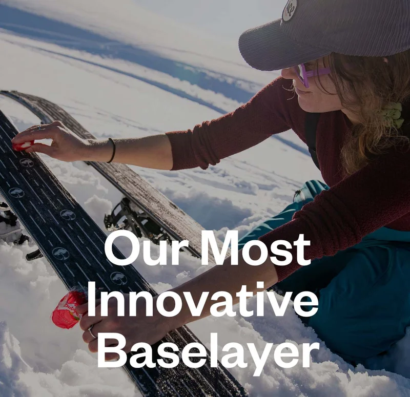 Patagonia 50. Our most innovative baselayer. A person kneeing in the snow rubs a small piece of cheese on the bottom of their skis.