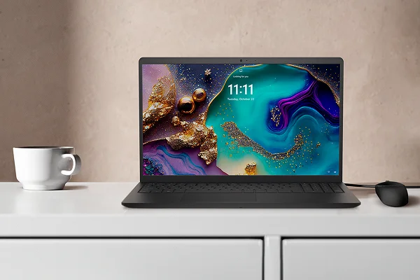 A Dell 15 Laptop next to a cup of coffee on a white countertop.