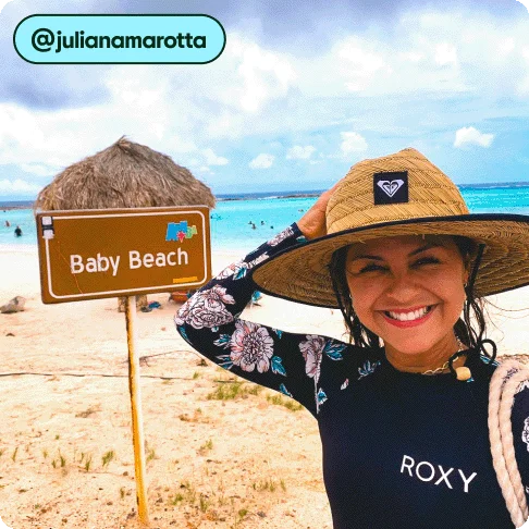 Image Description: A person posing by a sign at the beach that says “Baby Beach.”