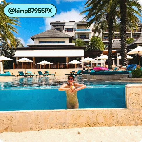 Image Description: A person posing for a photo in a pool at a resort.
