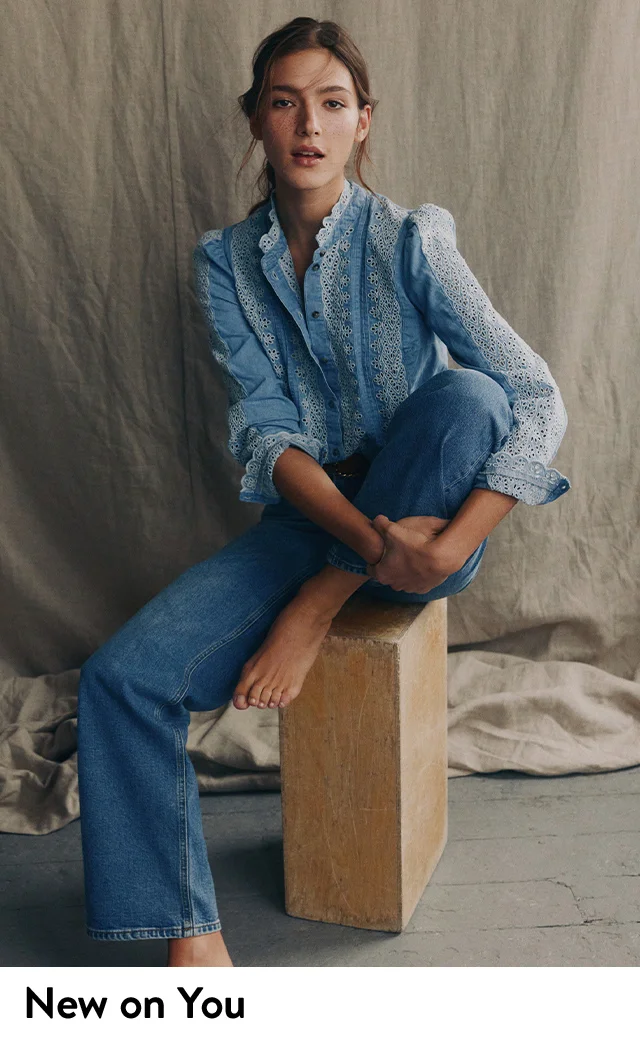 A woman wearing a lace-trim shirt and jeans.