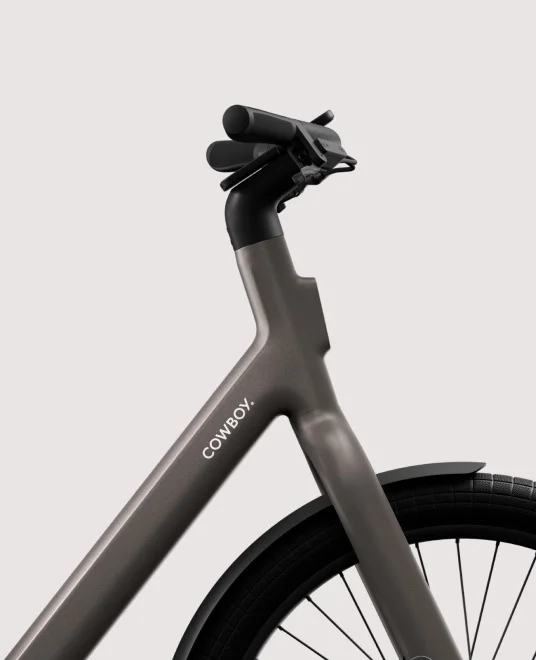 A render. Rear angled view of a Cowboy Cross ST e-bike with a cargo rack and integrated rear light.