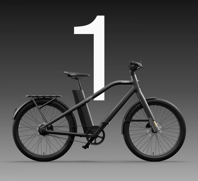 Front view of a Cowboy bike showcasing its sleek handlebars, integrated smartphone mount displaying navigation, and a minimalist rear luggage rack. The number “2” is prominently displayed in white against a dark gradient background.