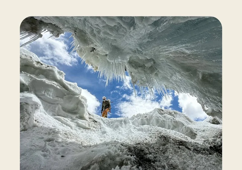 A mountaineer peers into a crevasse