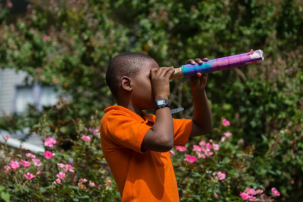 A child looks through a makeshift telescope