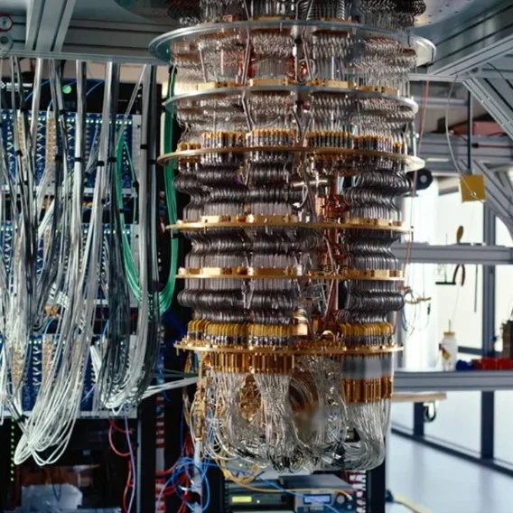 A complex network of golden wires and components, intricately layered and suspended within a cylindrical structure, resembles a futuristic chandelier.