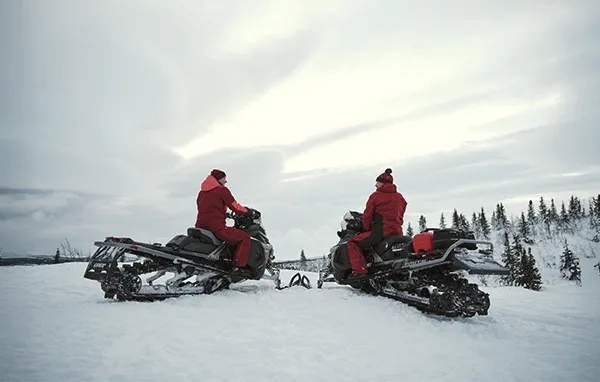 2 riders on their snowmobile on a hill