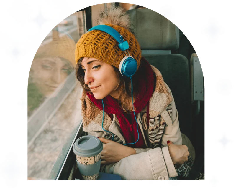 Thoughtful woman in the train looking through the window listening to headphones