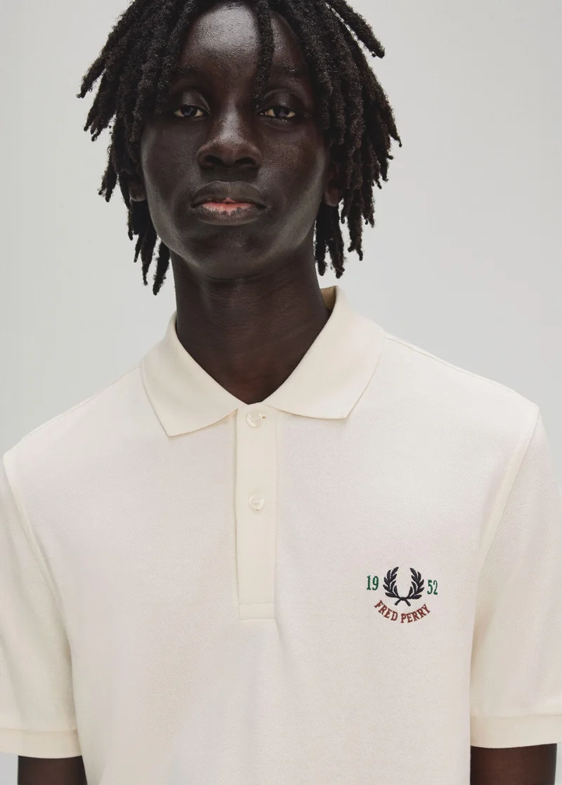 Man wears Clubhouse Embroidered Polo Shirt in colour Ecru