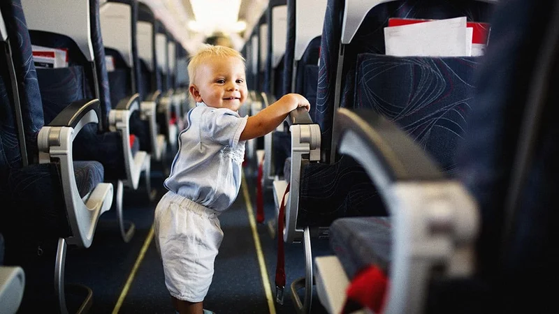 Image description: Small child standing in the aisle of an airplane