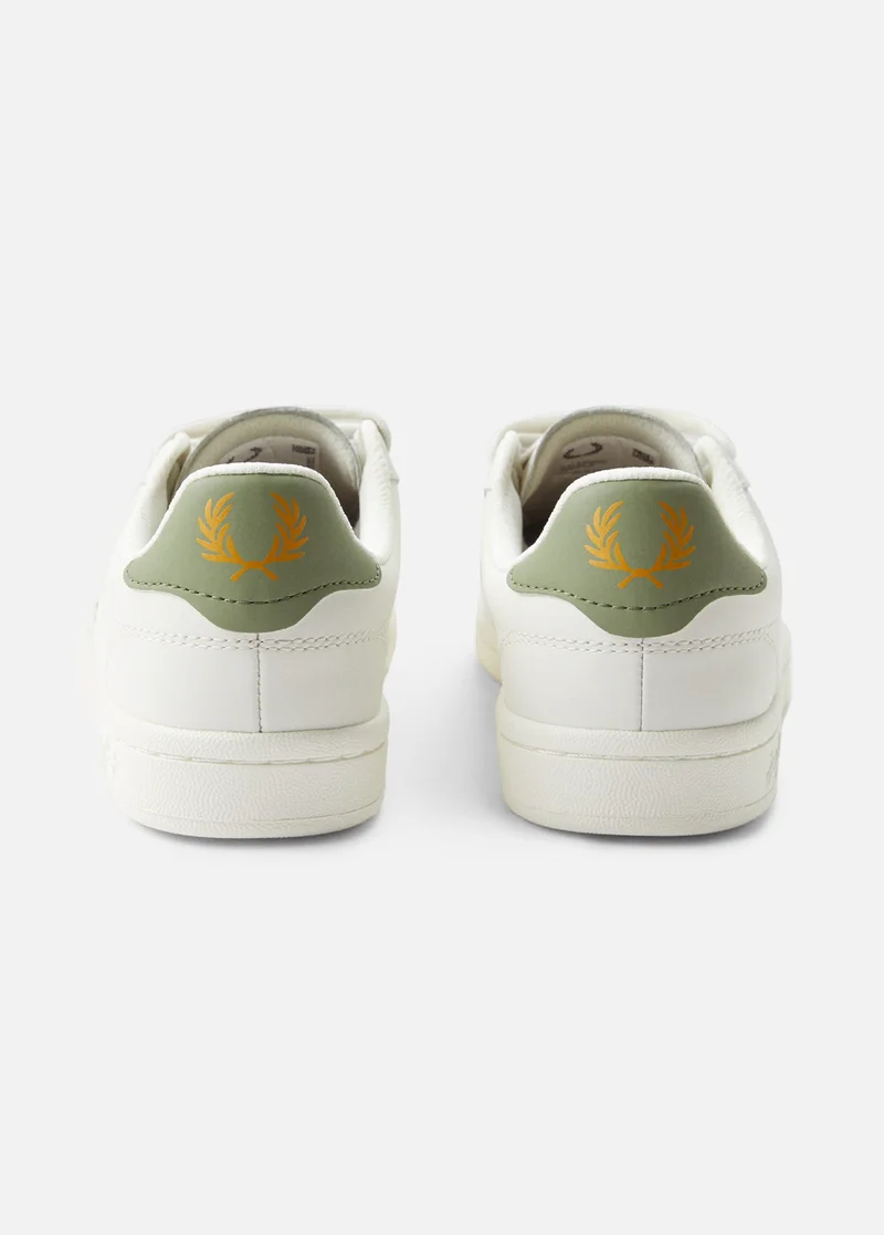 the back view of white trainers with a sage green heels embellished with gold laurel wreaths
