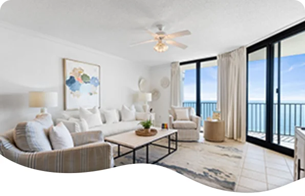 Bright coastal living room with white décor and floor‑to‑ceiling windows facing the ocean.