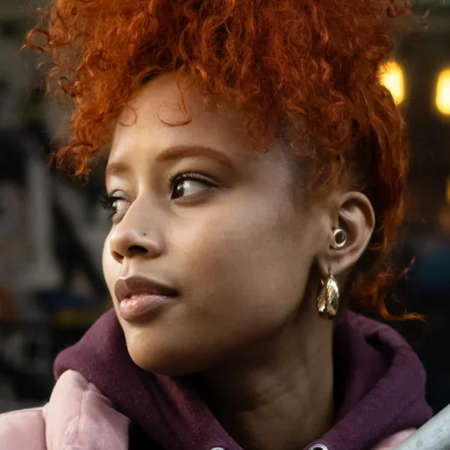 Woman looking away from the camera pensively while wearing Loop earplugs.
