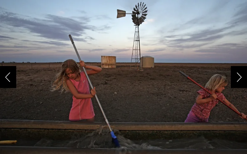 Sisters sweep out sludge from a watering trough on their family sheep farm in Ivanhoe, New South Wales, Australia. This photo appeared in an April 2009 issue about an extreme drought, known as the Millennium drought, that affected Australia for about 15 years.