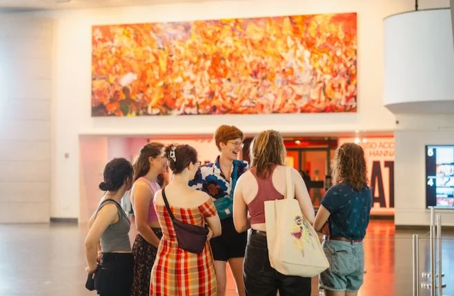 Three visitors standing in front of two artworks