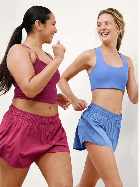 Two girls walking in red and blue solemate shorts and matching tops against a plain background.