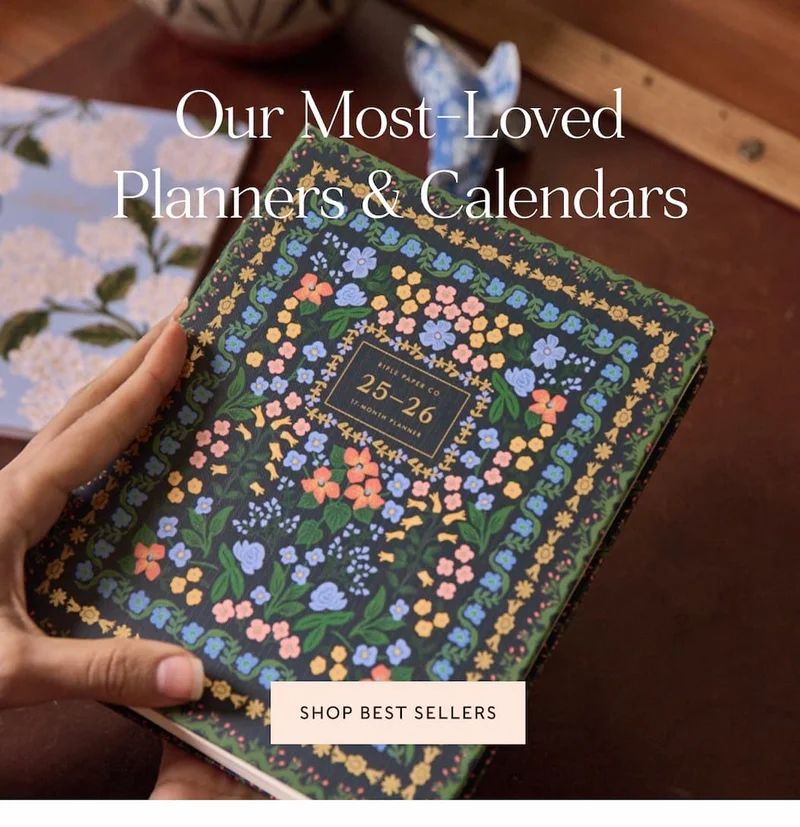 Hands holding a floral 2025-2026 planner with the text "Our Most-Loved Planners & Calendars" and a "Shop Best Sellers" button.